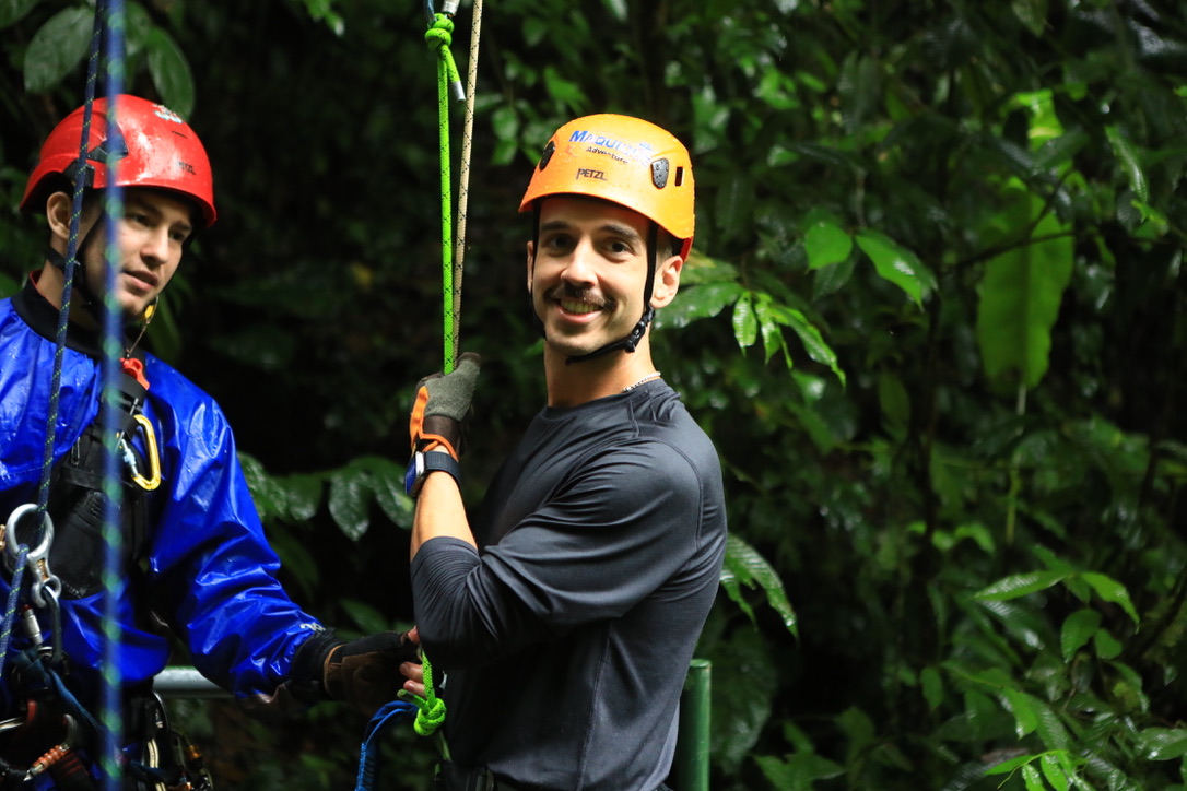 David smiling in an orange helmet while rock climbing